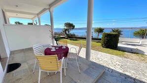 Un espacio de estar al aire libre con techo, con una mesa dispuesta para dos personas, con vista a un paisaje marino.