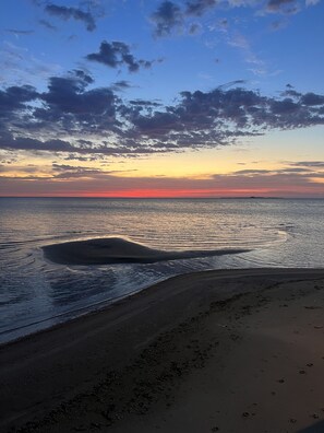 Une plage avec une mer calme et un coucher de soleil.