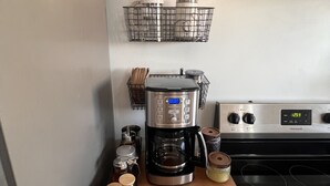 A kitchen with a coffee maker, a basket of tea bags, and a spice rack.