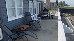A building with a covered patio area featuring outdoor seating and a view of the water.