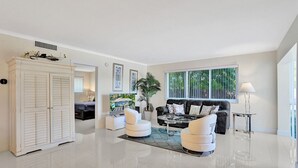 Ein geräumiges Wohnzimmer mit einem großen weißen Schrank, einer schwarzen Ledersofa und einem Glastisch.
