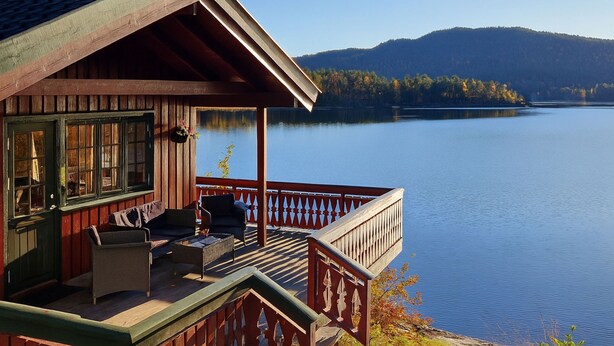 A wooden cabin with a balcony overlooking a calm lake and forested hills. - Midtholmen by Interhome (Konsmo)