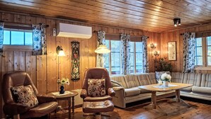 A cozy cabin interior with wooden walls and floors, a leather armchair, a sofa, and a small table with a vase of flowers. - Midtholmen by Interhome (Konsmo)