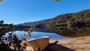 A boat on a calm lake with a forested hillside in the background. - Midtholmen by Interhome (Konsmo)