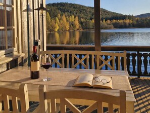 A wooden deck with a table, a bottle of wine, and an open book. - Staksholmen by Interhome (Konsmo)