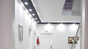 A hallway with a marble floor, a fire extinguisher, and a staircase. - Hotel Delmar (Golem)