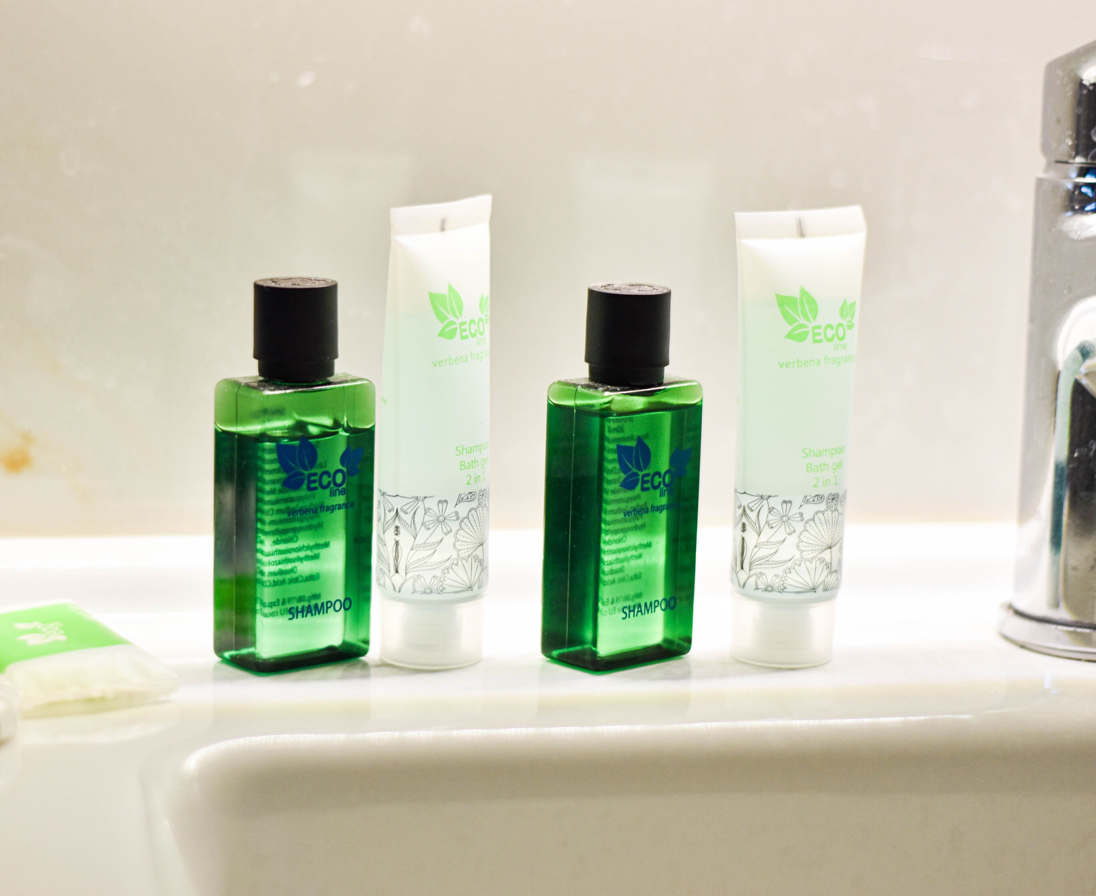 Tres botellas de champú y gel de baño de la línea ECO sobre un lavamanos.