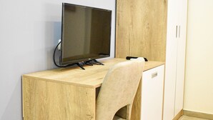 A room with a wooden desk, a chair, a television, and a wardrobe. - Hotel Delmar (Golem)