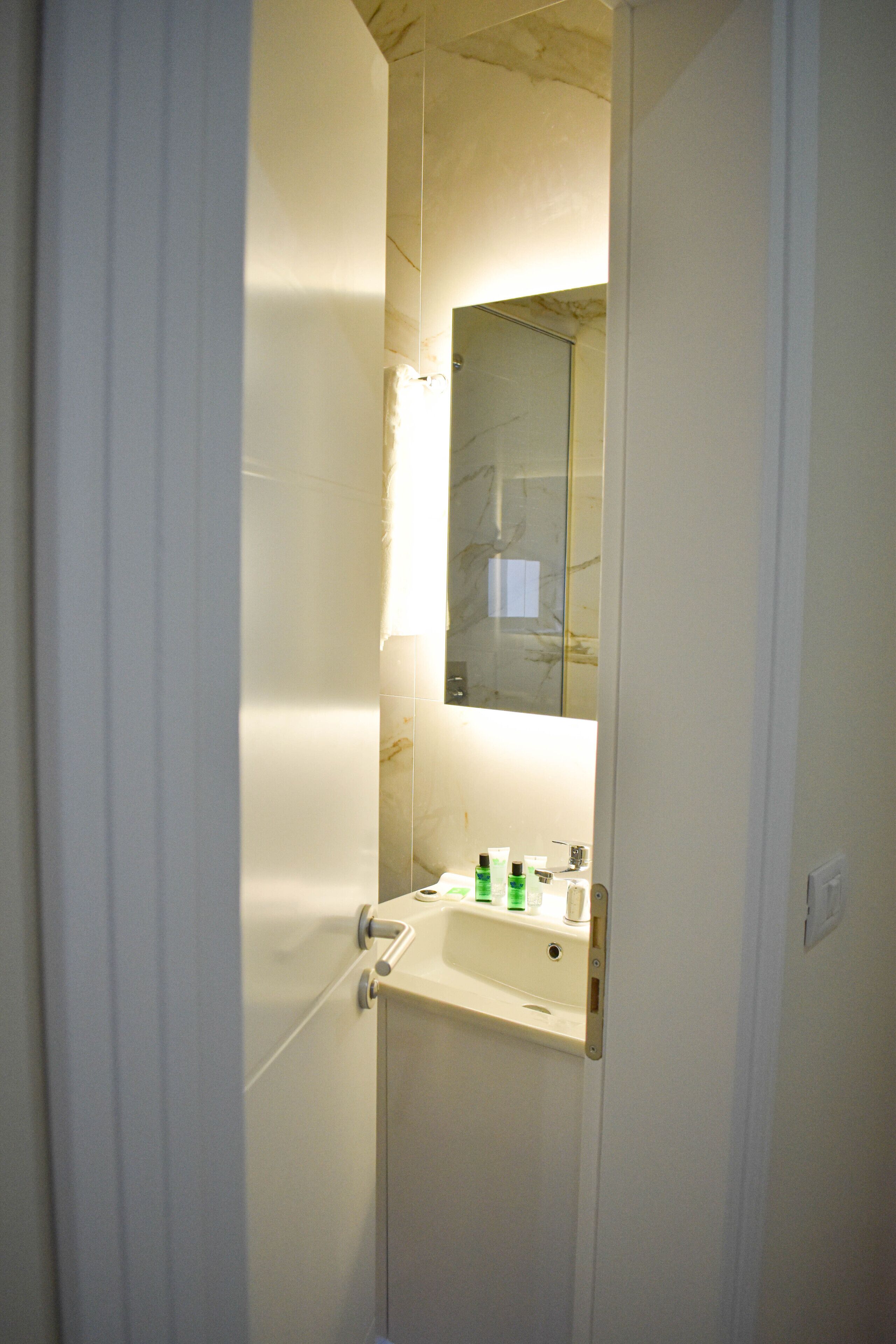 A bathroom with a sink, mirror, and toiletries.