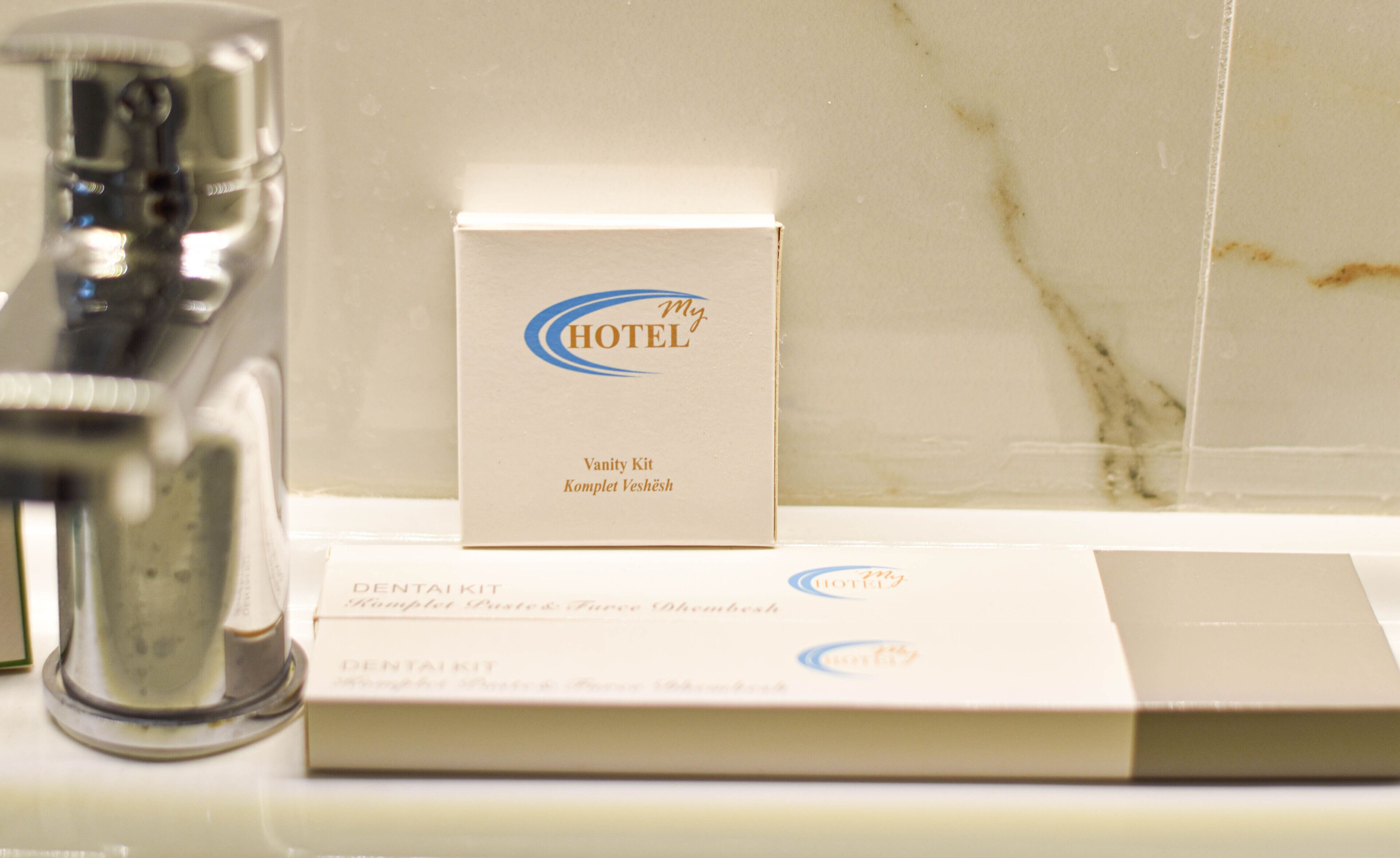 A bathroom sink with a mirror, a toothbrush holder, and a box labeled "My Hotel Vanity Kit."