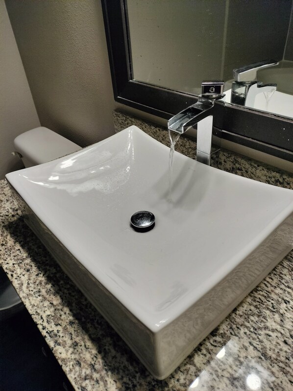 Un baño con lavamanos blanco, grifo y retrete.