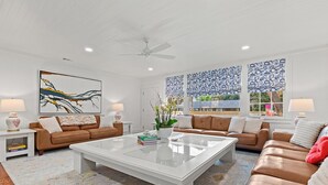 Ein modernes Wohnzimmer mit zwei braunen Ledersofas, einem weißen Couchtisch und einem großen, abstrakten Gemälde an der Wand.