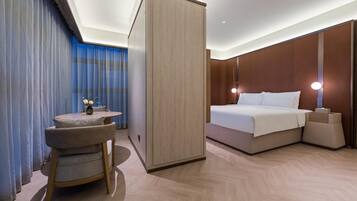 A hotel room with a bed, bedside table, and a small seating area with a chair and table.