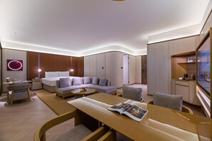 A modern hotel room with a bed, sofa, and armchairs, a dining table with magazines, and a TV mounted on the wall. - Crystal Orange Hotel Haimen Wenfeng Great World (Nantong)