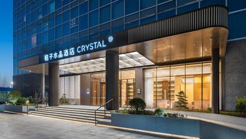 Entrada de hotel com uma placa indicando 'CRYSTAL' e design arquitetônico moderno.