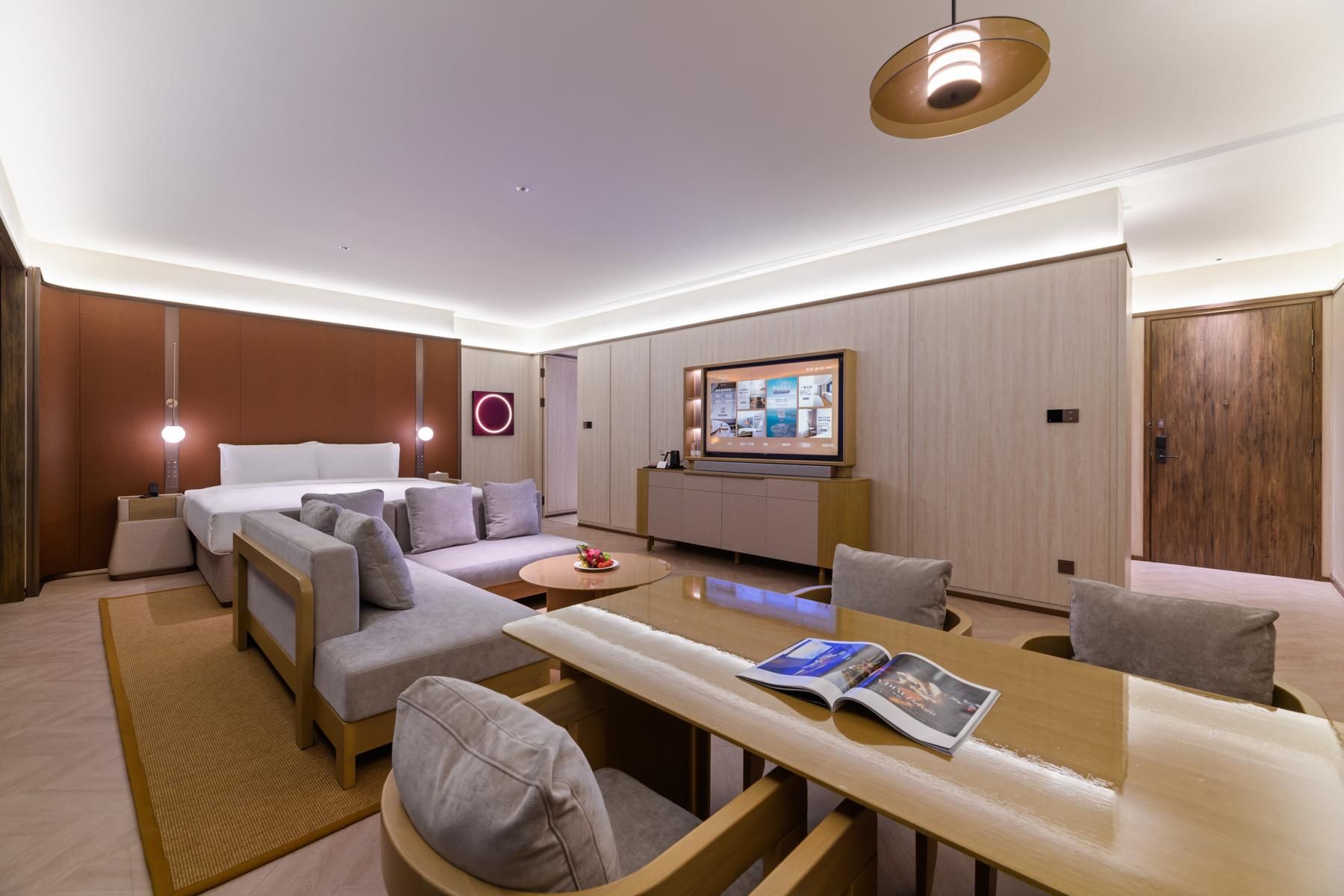 Une chambre d’hôtel moderne équipée d’un canapé, d’une table à manger, d’un téléviseur et d’une armoire en bois.
