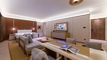 Une chambre d’hôtel moderne équipée d’un canapé, d’une table à manger, d’un téléviseur et d’une armoire en bois.
