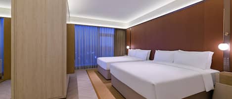 A modern hotel room with two beds, a large wardrobe, and a view of the city at night.