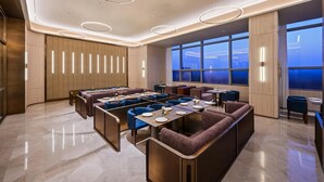 A modern dining area with booth seating, a long counter, and a view of the cityscape through large windows. - Crystal Orange Hotel Haimen Wenfeng Great World (Nantong)