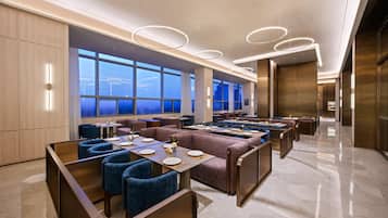 A modern dining area with high ceilings, large windows, and contemporary lighting fixtures.