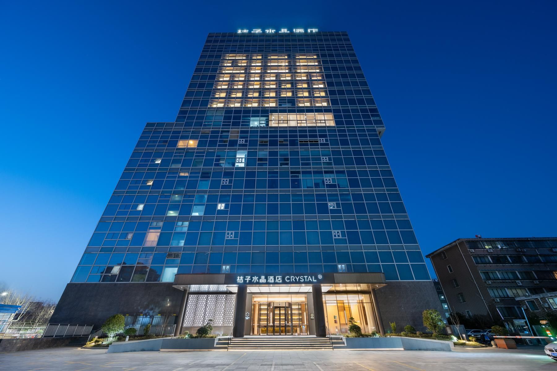Un moderno edificio de hotel con fachada de vidrio, una entrada destacada y un letrero que dice "CRYSTAL".