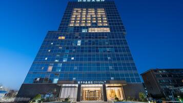 A modern hotel building with a glass facade, a prominent entrance, and a sign reading "CRYSTAL".