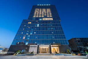A modern hotel building with a glass facade and a prominent entrance. - Crystal Orange Hotel Haimen Wenfeng Great World (Nantong)