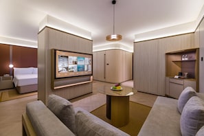 A modern hotel room with a bed, a TV mounted on a wall, a round table with a fruit bowl, and a sofa. - Crystal Orange Hotel Haimen Wenfeng Great World (Nantong)