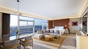 Habitación de hotel moderna con una cama grande, un sofá, un comedor y vistas a la ciudad.