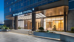 A hotel with a modern facade, a prominent sign reading "CRYSTAL", and a well-lit entrance with steps leading up to the doors. - Crystal Orange Hotel Haimen Wenfeng Great World (Nantong)