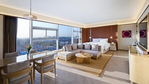 A modern hotel room with a large bed, a sofa, a dining table, and a TV. The room has large windows offering a city view. - Crystal Orange Hotel Haimen Wenfeng Great World (Nantong)