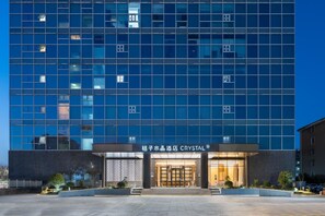 A modern hotel with a glass facade, a well-lit entrance, and a sign indicating the name 'CRYSTAL'. - Crystal Orange Hotel Haimen Wenfeng Great World (Nantong)