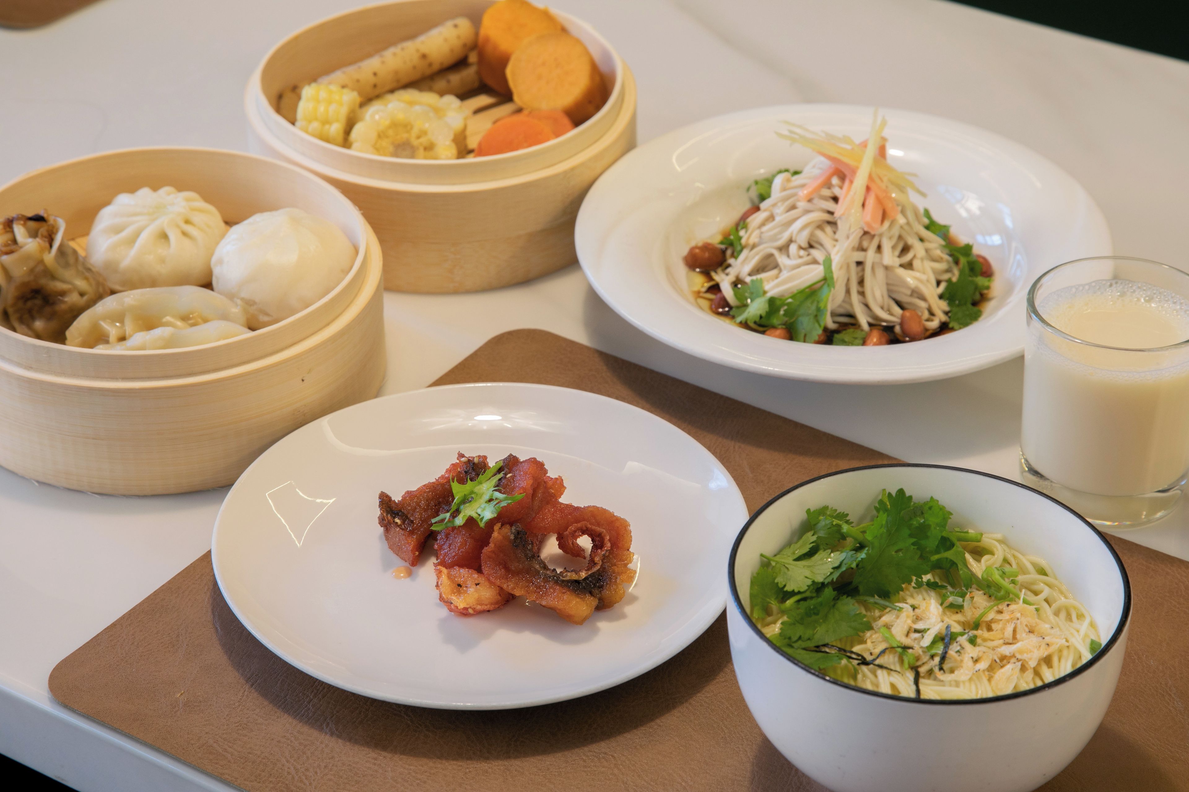 A table with various dishes including dumplings, a salad, and noodles.