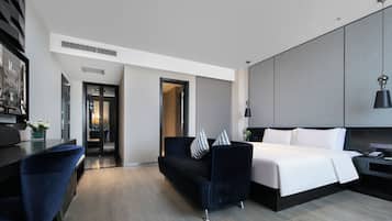 A modern hotel room with a bed, a desk, a sofa, and a wardrobe.