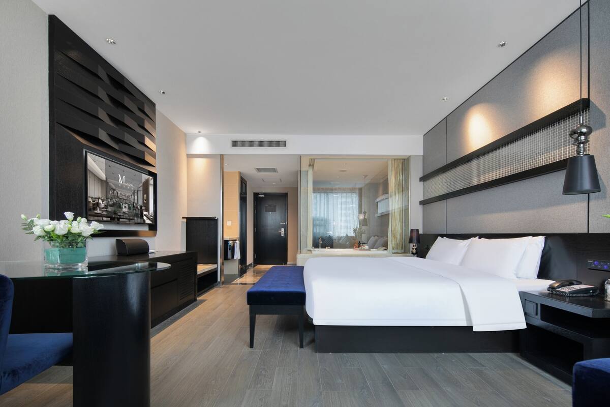 Una habitación de hotel moderna con una cama grande, un escritorio y una zona de estar.