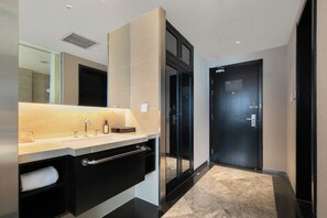 A modern bathroom with a large mirror, a sink, a towel rack, and a glass shower enclosure. - Crystal Orange Hotel Taizhou Maoye Tiandi (Taizhou)