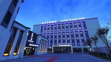 A hotel with a modern facade, multiple floors, and a red carpet entrance.