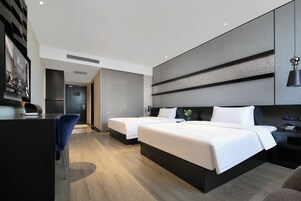 A modern hotel room with two beds, a desk, and a chair.