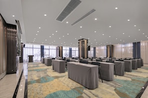 A conference room with multiple tables, a patterned carpet, and a modern ceiling design.