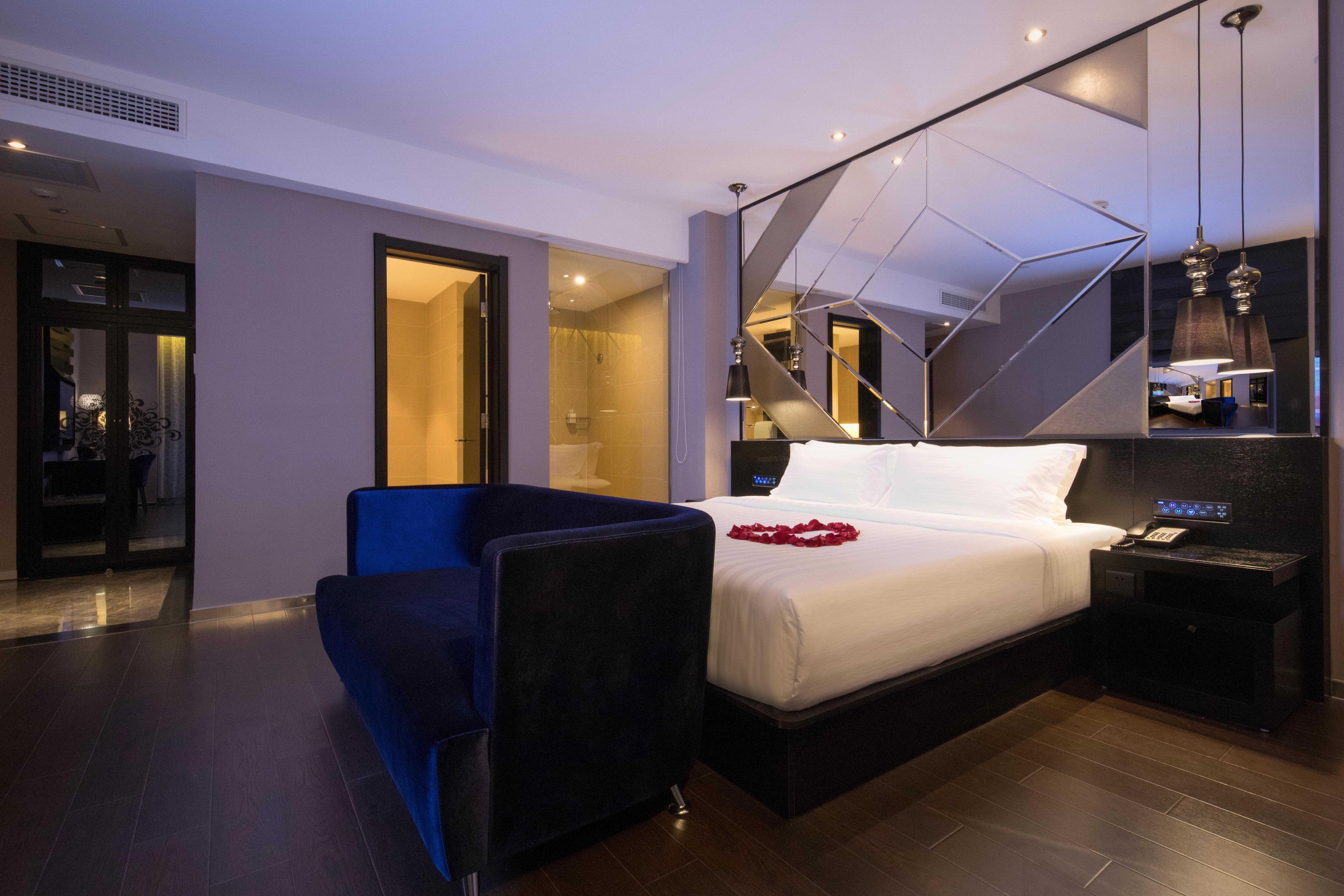 Habitació d'hotel moderna amb un llit gran, un escriptori, una cadira i un mirall.