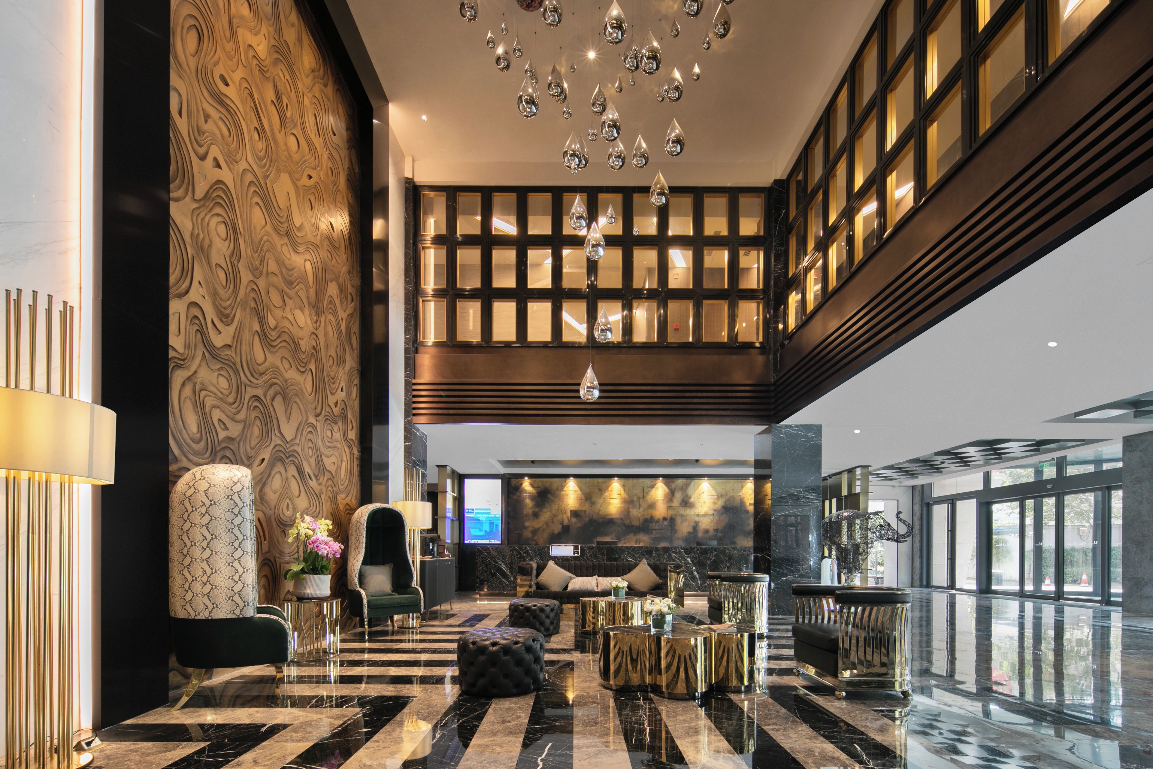 A spacious lobby with a high ceiling, a marble floor, and a seating area with a sofa and armchairs.