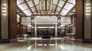 Un'ampia hall con soffitto alto, travi in legno e un lampadario centrale.