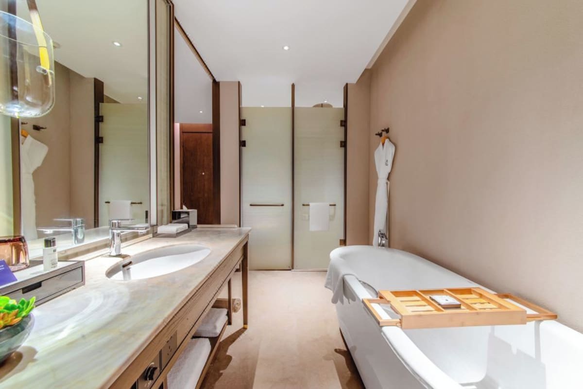 Un baño moderno con un espejo grande, dos lavamanos, una bañera y zona de ducha.