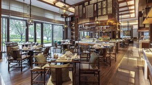 Un'ampia sala ristorante con soffitti alti, grandi finestre e arredamento in legno tradizionale.