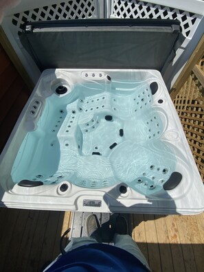 A hot tub with multiple jets, a control panel, and a wooden deck surrounding it. - 2 bedroom in Logan Ohio, Hocking Hills, Luxury Hot Tub, King Size Bed, Fire-pit (Logan)