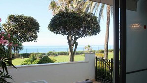 A balcony with a view of the sea, a glass table, and a black metal fence. - Beachfront apartment with sea views. (Estepona)