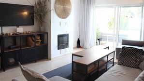 A modern living room with a flat-screen TV, a fireplace, a dining table, and a sofa. - Beachfront apartment with sea views. (Estepona)
