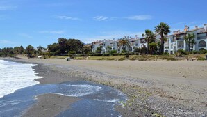 A beachfront hotel with multiple-story buildings, a sandy beach, and palm trees. - Beachfront apartment with sea views. (Estepona)