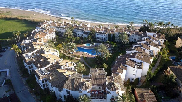 A coastal resort with multiple villas, a central swimming pool, and a beach view. - Beachfront apartment with sea views. (Estepona)