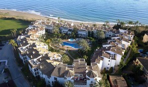 A coastal resort with multiple villas, a central swimming pool, and a beach view.